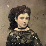 Mystical Looking Young Woman in Black Dress with Cross, Curls, and Heart-like Butterflies