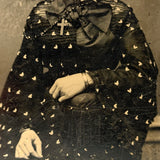 Mystical Looking Young Woman in Black Dress with Cross, Curls, and Heart-like Butterflies