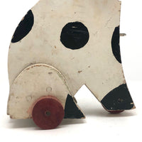 Old Black and Spotted Wooden Dog on Wheel