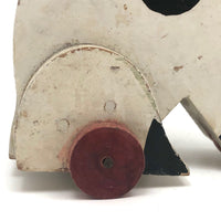 Old Black and Spotted Wooden Dog on Wheel